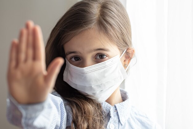 A cute little girl in a disposable protective mask from the coronavirus. Stop coronavirus concept.