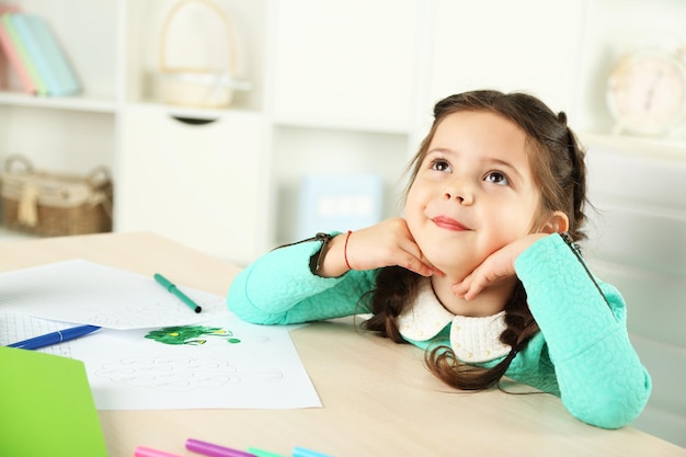 Photo cute little girl doing her homework closeup on home interior background