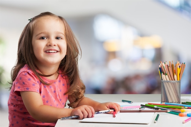 Cute little girl doing homework, reading a book, coloring pages, writing and painting.