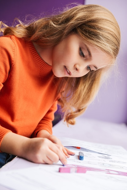 Cute little girl drawing in a coloring book indoors