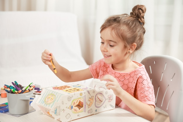 Disegno sveglio della bambina con le matite a casa