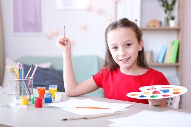 Cute little girl draws paints at home