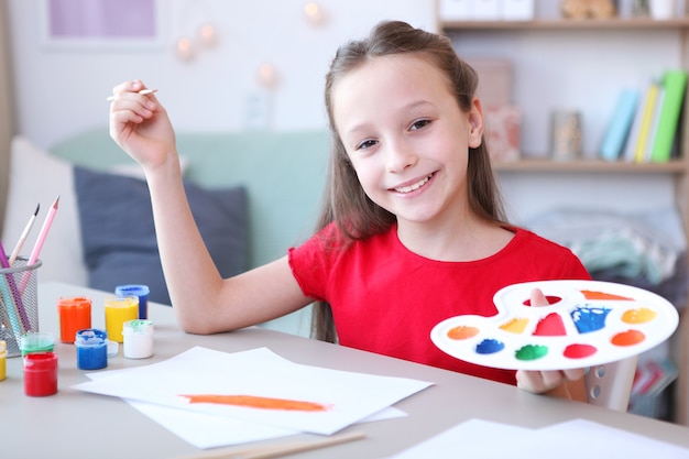 Cute little girl draws paints at home