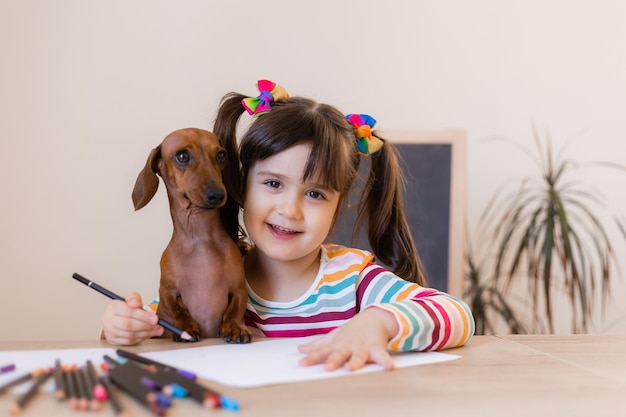 かわいい女の子が友達の犬ダックスフントと一緒に描きます。子供や動物、犬に優しい高品質です。