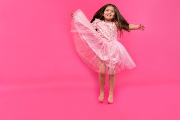 Cute little girl dreams of becoming a ballerina. Little Dancing Girl. Studio Shoot Over Pink Background.