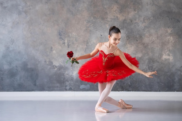 A cute little girl dreams of becoming a professional ballerina A girl in a bright red tutu on pointe shoes dances in the hall Vocational school student