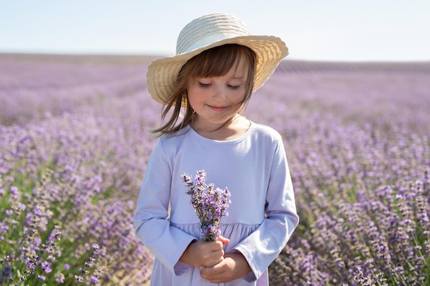 A cute little girl in a dress and a straw hat in a lavender field Provence