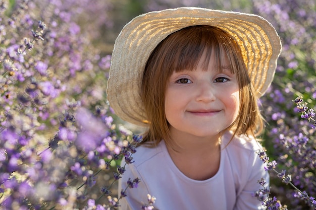 A cute little girl in a dress and a straw hat in a lavender field Provence