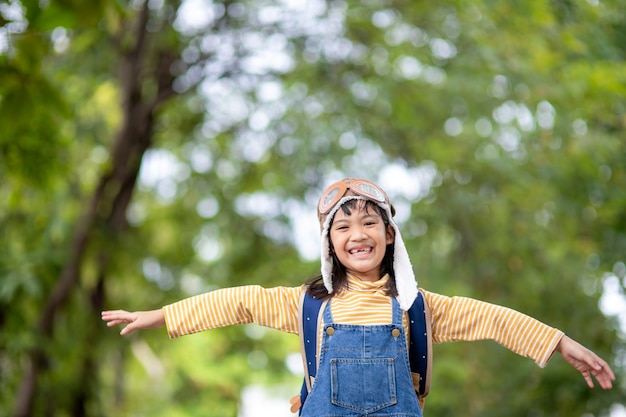 A cute little girl dressed in a cap and glasses of a pilot. The child dreams of becoming a pilot.