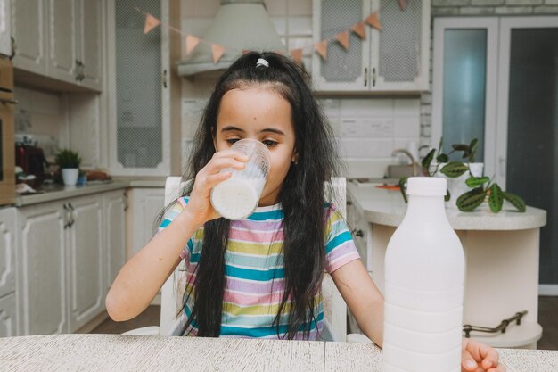 Cute little girl drinks milk at the table in the kitchen the child is holding a bottle of milk mocap