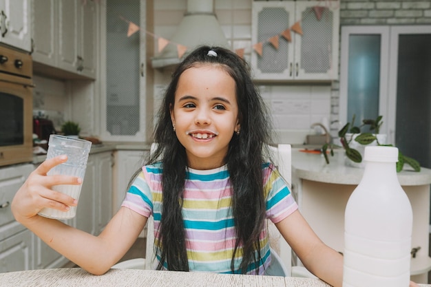 Cute little girl drinks milk at the table in the kitchen the child is holding a bottle of milk mocap