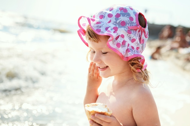 Bambina sveglia che mangia il gelato in vacanza al mare