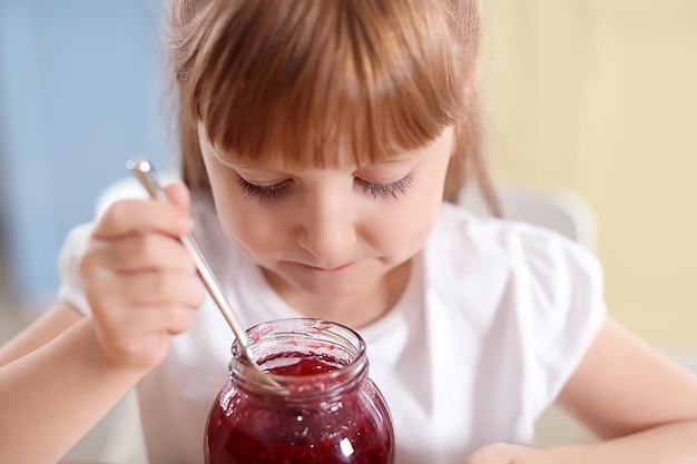 Cute little girl eating jam at home