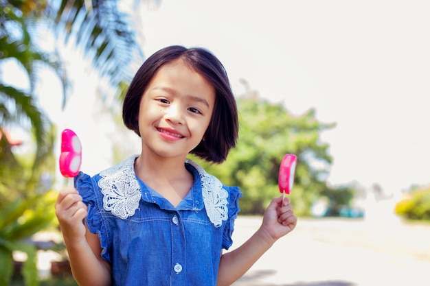 Photo cute little girl eating popsicle with sunset