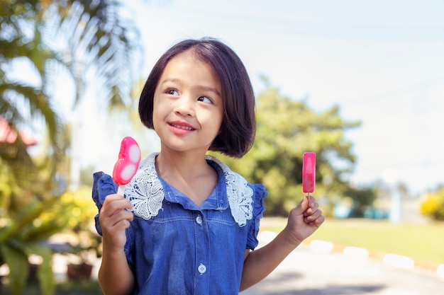 Cute little girl eating popsicle with sunset