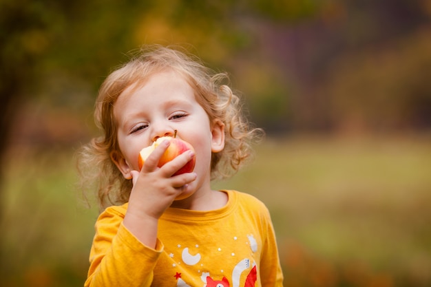 Bambina sveglia che mangia mela deliziosa rossa