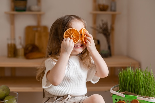 Cute little girl eats natural pastille at home in a wooden kitchen.