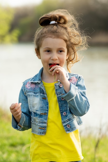 A cute little girl eats strawberries.