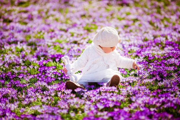 Cute little girl enjoying spring and sun among the spring flowers crocuses