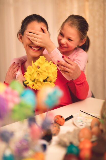 Cute little girl giving her mother bouquet yellow daffodils.