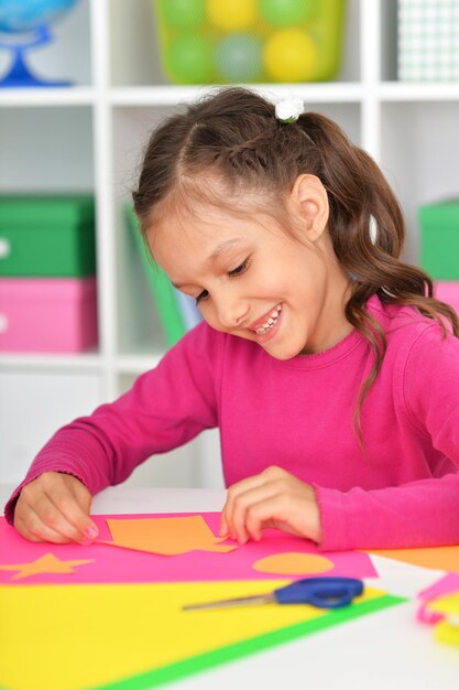 Cute little girl gluing paper