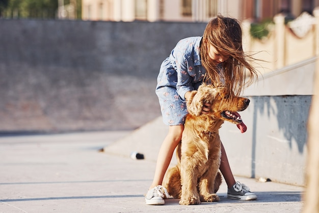 Cute little girl have a walk with her dog outdoors at sunny day