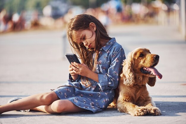 Cute little girl have a walk with her dog outdoors at sunny day