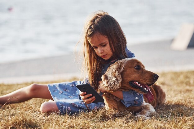 Cute little girl have a walk with her dog outdoors at sunny day