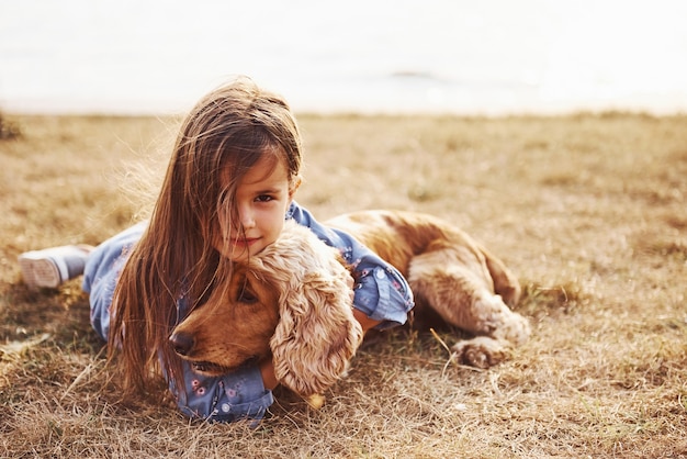 Cute little girl have a walk with her dog outdoors at sunny day