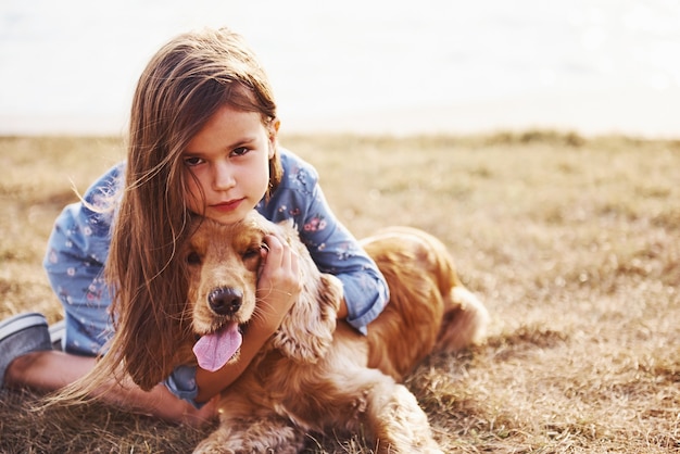 Cute little girl have a walk with her dog outdoors at sunny day