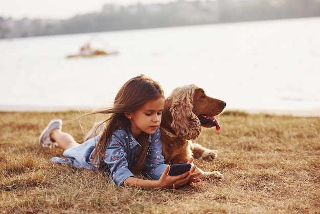 Cute little girl have a walk with her dog outdoors at sunny day