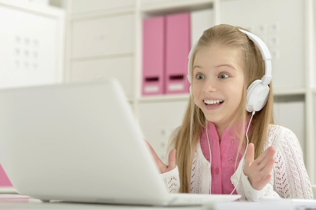 Cute little girl  in headphone with  laptop at home