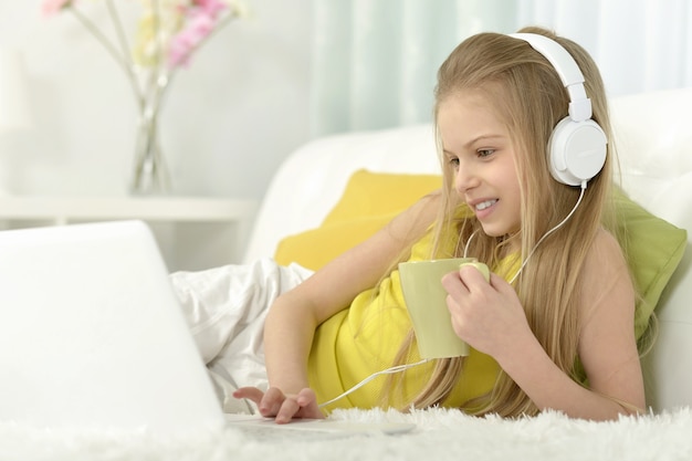 Cute little girl  in headphone with  laptop at home