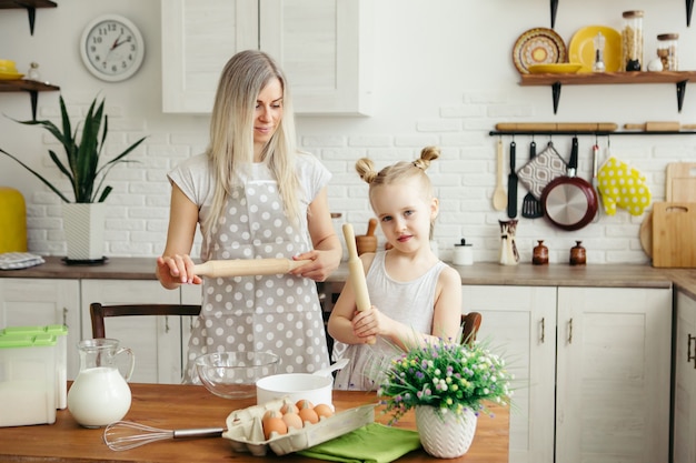 Cute little girl helps mom bake cookies in the kitchen. Happy family. Toning.