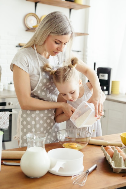 Милая маленькая девочка помогает маме печь печенье на кухне. Счастливая семья. Тонировка.
