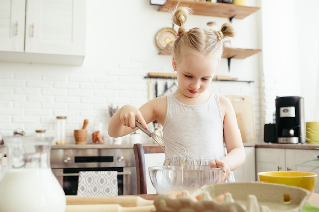 Cute little girl helps mom bake cookies in the kitchen. Happy family. Toning.