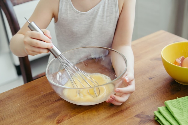 かわいい女の子は、お母さんがキッチンでクッキーを焼くのを手伝います。幸せな家族。調色。