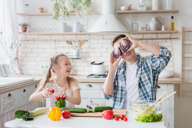 Bambina carina e suo padre che si divertono mentre cucinano in cucina a casa