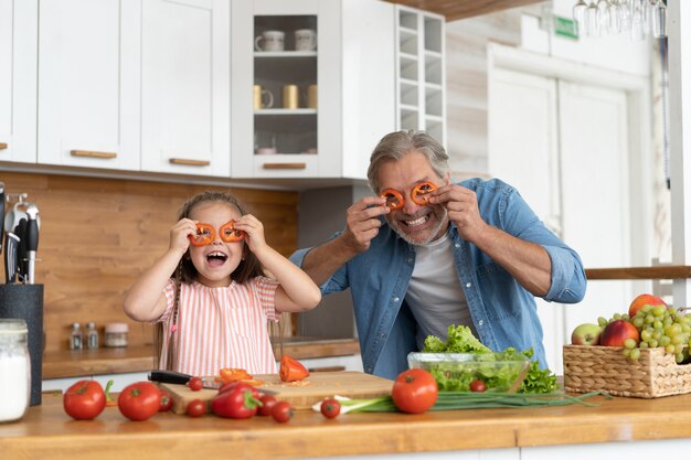 Cute little girl and her handsome dad are having fun while cooking in kitchen at home.