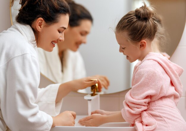 Foto una bambina carina e sua madre si stanno lavando le mani sotto l'acqua corrente