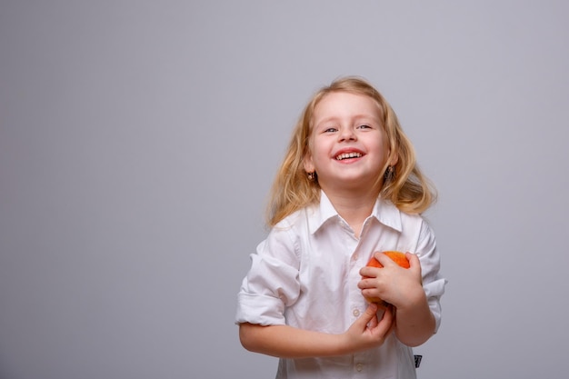 Милая маленькая девочка держит яблоко на белом фоне
