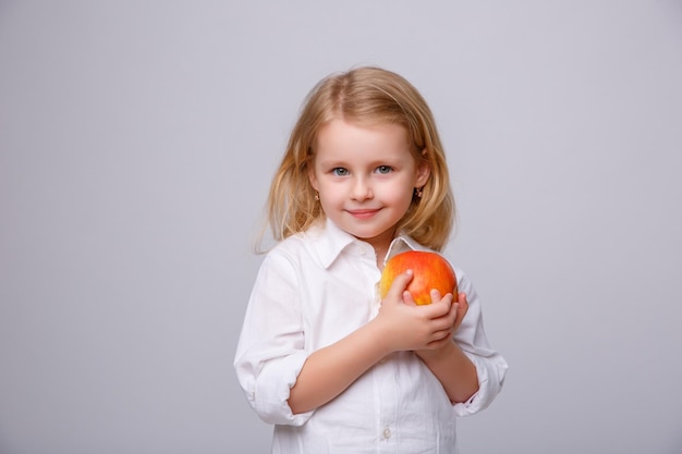 Cute little girl holding an apple on a white background