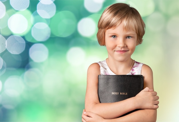 Cute little girl holding Bible on  background