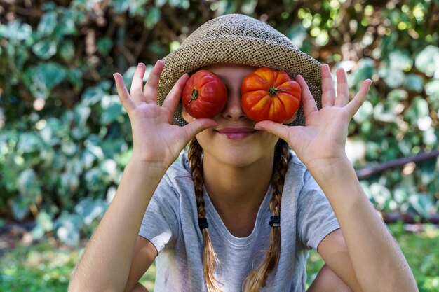 Bambina sveglia che tiene un mazzo di pomodori organici freschi