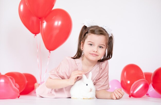 Cute little girl holding a bunch of red heartshaped balloons