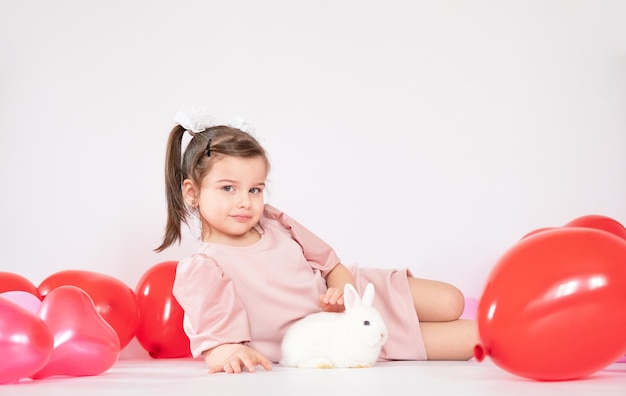 Cute little girl holding a bunch of red heartshaped balloons