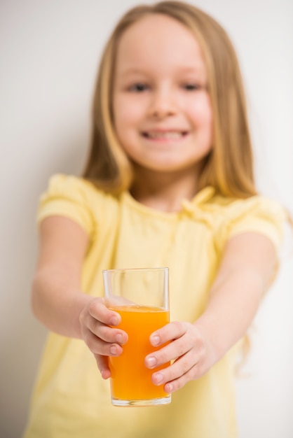 Photo cute little girl holding a glass of juice