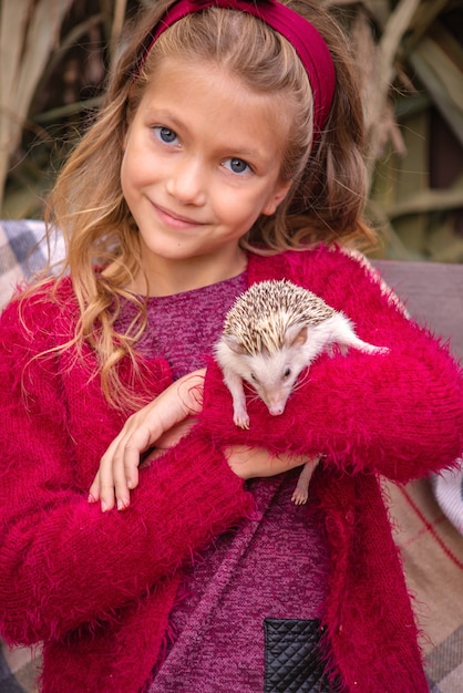 cute little girl holding a hedgehog in her arms autumn portrait