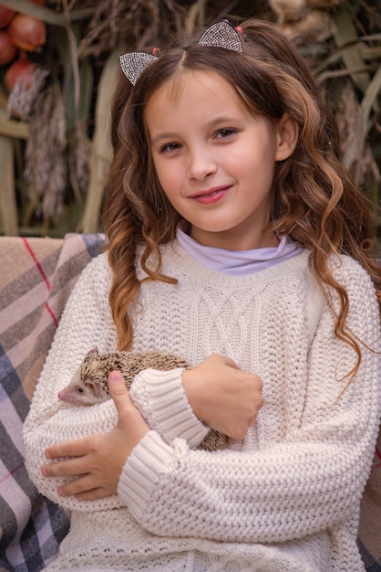 cute little girl holding a hedgehog in her arms autumn portrait