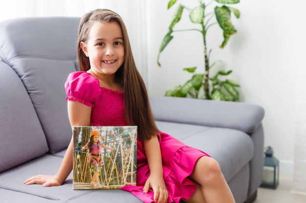 Bambina sveglia che tiene la tela fotografica a casa